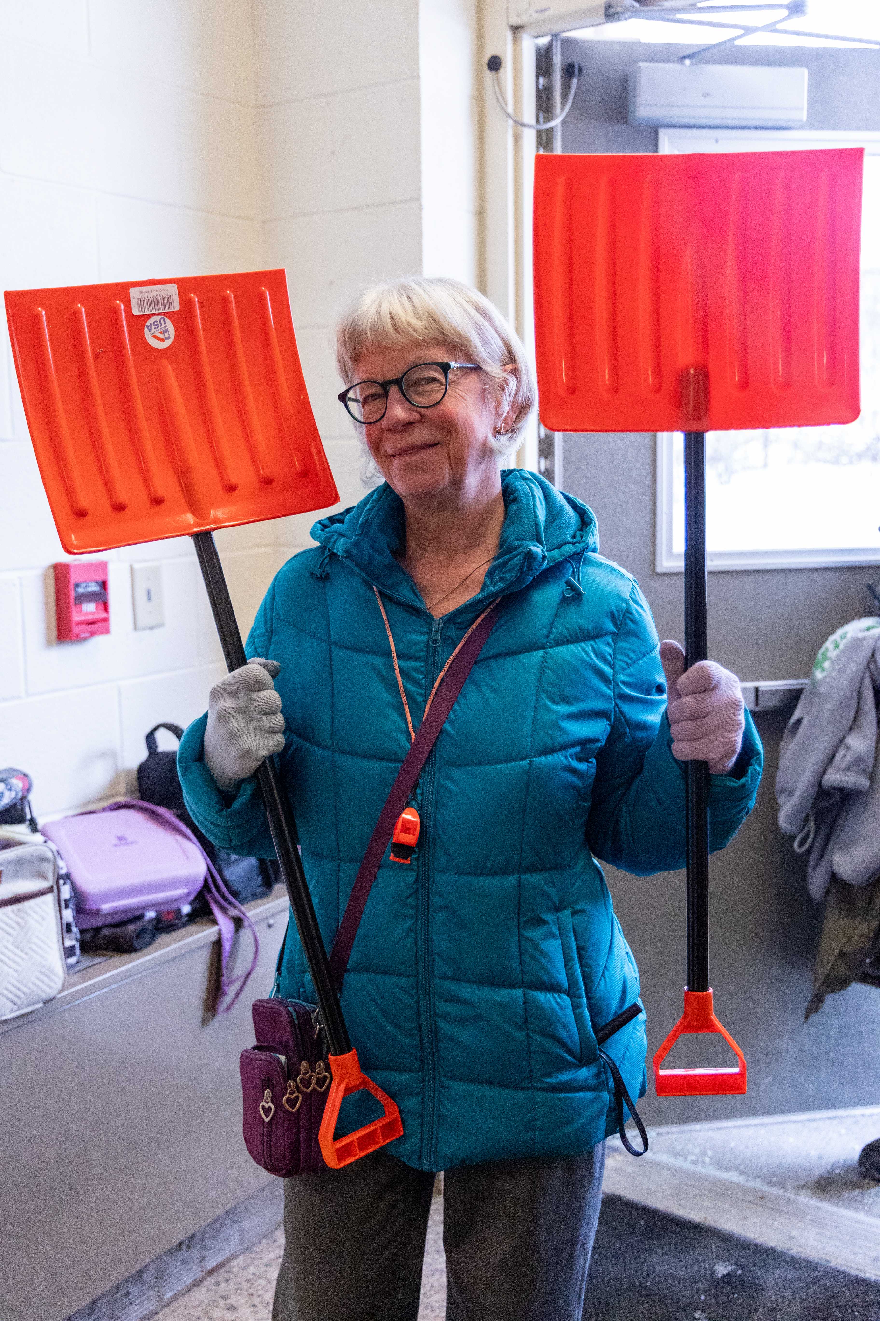 Ms. Patty poses with two shovels, ready for the winter snow outside.